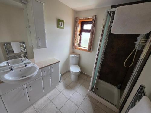 a bathroom with a sink and a shower and a toilet at Peedie Sea Accommodation in Orkney