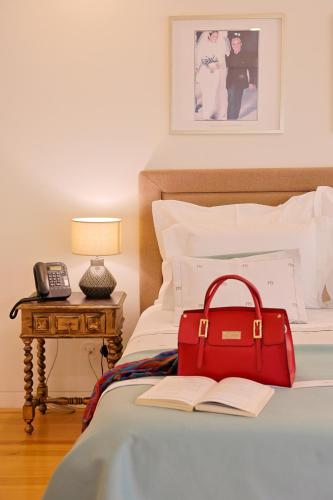 a red bag sitting on a bed with a book at TM Luxury Apartments Lisbon in Lisbon