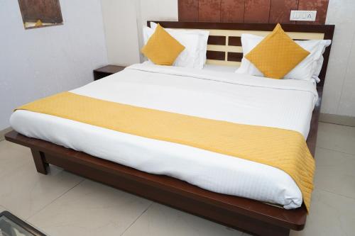 a bedroom with a large bed with yellow and white pillows at Hotel The Bliss Near Housing Board Chowk Mani Majra Chandigarh in Chandīgarh