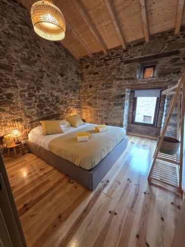 a bedroom with a bed and a stone wall at Pátio do Tear in Sobreira Formosa