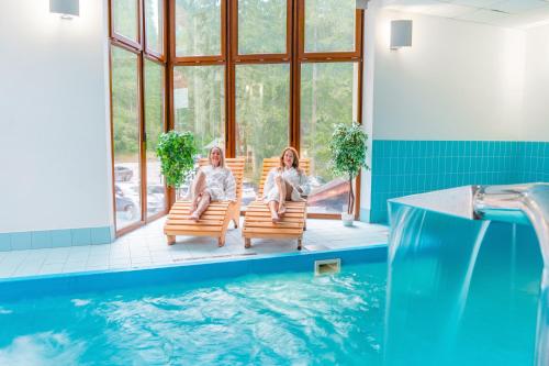 two women sitting in chairs next to a swimming pool at Relax hotel FIM in Belá