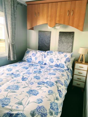 a bedroom with a bed with a blue and white comforter at Ailsa Seaview in Turnberry