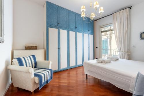 a bedroom with a bed and a chair and a chandelier at Hostdomus - Salsedine Apartment in Alassio