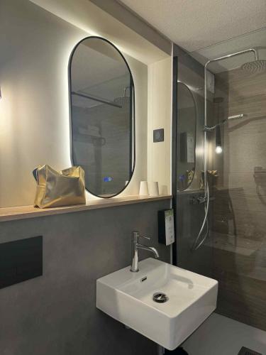 a bathroom with a sink and a mirror and a shower at Campanile NATURE -Haguenau in Haguenau