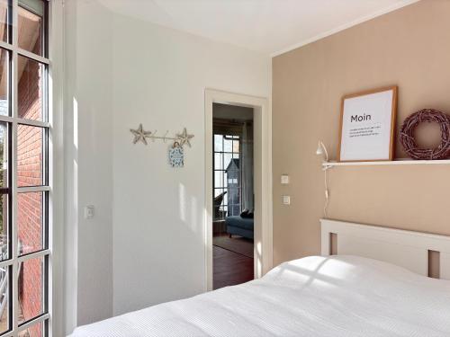 a white bedroom with a bed and a window at Ferienwohnung MEERWEH in Fehmarn