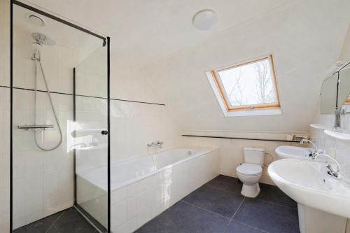 a bathroom with a tub and a sink and a toilet at Comfort Villa for 8 People in Zeewolde