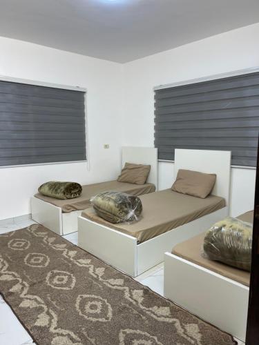 three beds with pillows on them in a room at درة عبين الدور الارضي 2 in ‘Ibbīn