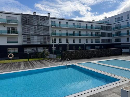 a swimming pool in front of a building at Azores Lava Apartment T3 in Ponta Delgada