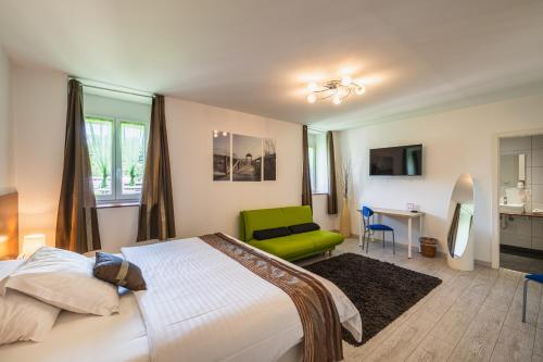 una camera da letto con un letto e una sedia verde di Hôtel Terminus a Porrentruy
