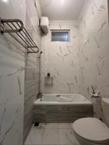 a white bathroom with a tub and a toilet at RBD Guest House in Ungaran