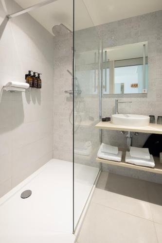 a white bathroom with a shower and a sink at Beach Hotel Helios by CW Hotel Collection in Blankenberge