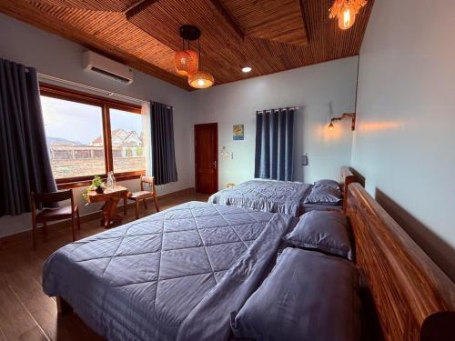 a bedroom with two beds and a table and a window at Homestay JB Sơn Hải in Thôn Sơn Hải