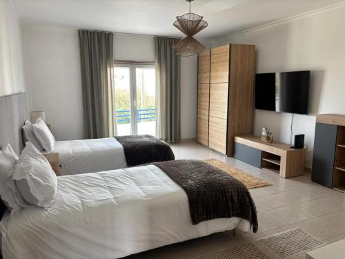a hotel room with two beds and a television at Apartamento - The Light House in Peniche