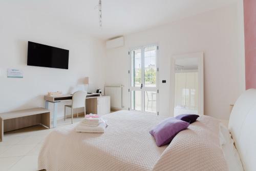 a white bedroom with a bed with purple pillows at Lamendolara B&B in Specchia