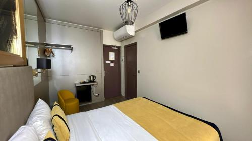 a hotel room with a bed and a tv at Pratic Hotel in Paris