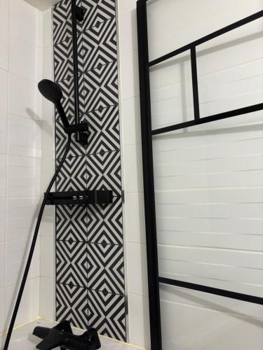 a shower with a black and white wall at La Parenthèse in Chalons en Champagne