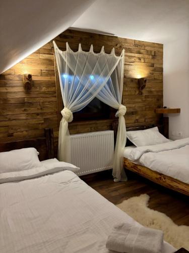 a bedroom with two beds and a window with curtains at JakLak in Izvoare
