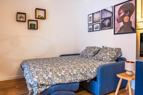 a bedroom with a blue bed and pictures on the wall at Studio Élégant - Proche Paris & La Défense in Rueil-Malmaison