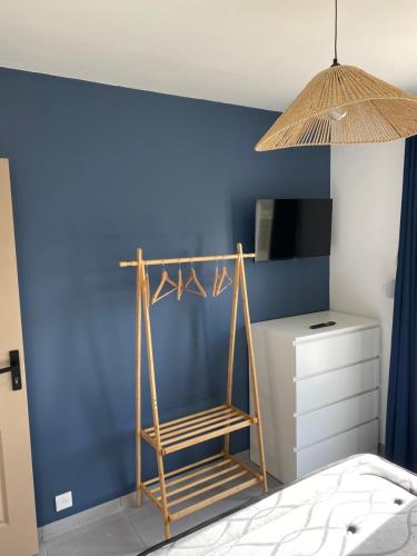 a bedroom with a blue wall and a wooden ladder at Gîte la pause en baie in Pendé