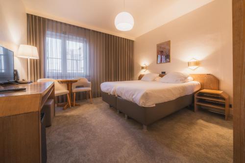 una camera d'albergo con un letto e una scrivania di Hotel Prado a Ostenda