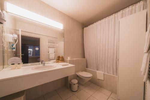 un bagno con lavandino, WC e specchio di Hotel Prado a Ostenda