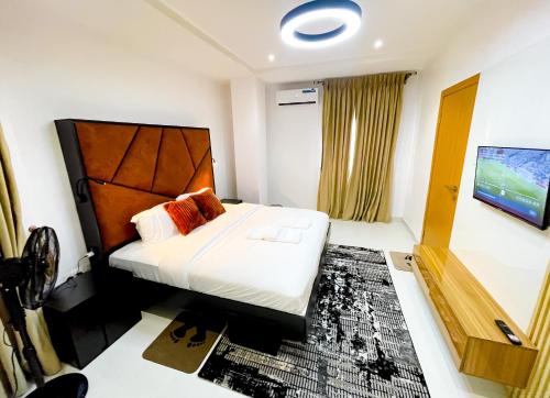a hotel room with a bed and a flat screen tv at LetMax Homes in Ikeja