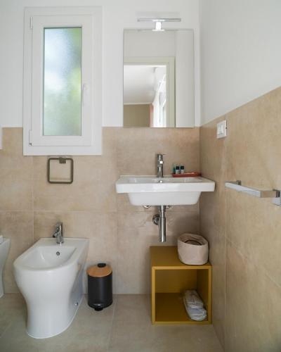 a bathroom with a sink and a toilet and a mirror at Otium Mare Felix in Stazione di Paestum