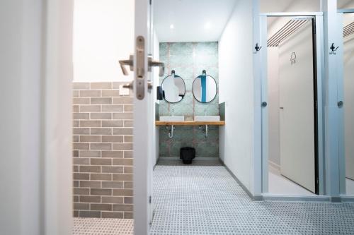 a bathroom with a walk in shower and two mirrors at Koba Hostel in San Sebastián