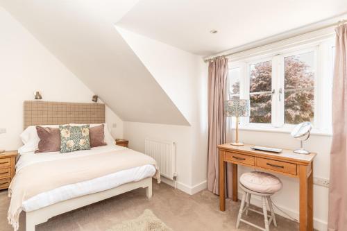 a bedroom with a bed and a desk and a window at Tokenhill Cottage in Dorchester
