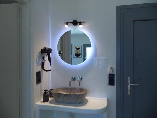a bathroom with a sink with a circular mirror at Sea Melody Studios in Plaka