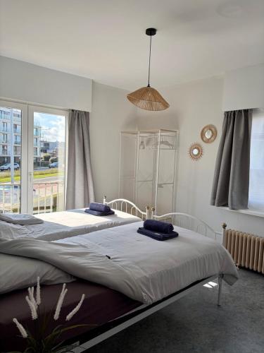 a bedroom with two beds and a large window at Sea You Soon in De Haan