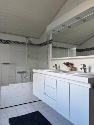 a white bathroom with two sinks and a mirror at Sea You Soon in De Haan