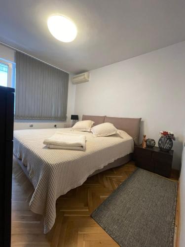 a bedroom with a bed with white sheets and a rug at Катедрала Варна in Varna City