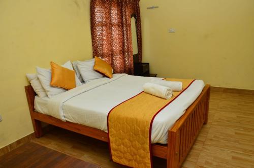 a bed with orange and white pillows in a room at Redfox Villa - Kodaikanal in Kodaikānāl