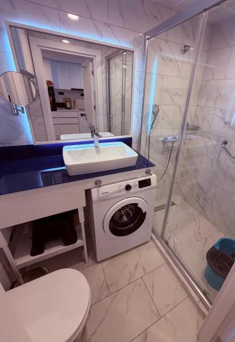a bathroom with a sink and a washing machine at Sun Set Apartments in Batumi