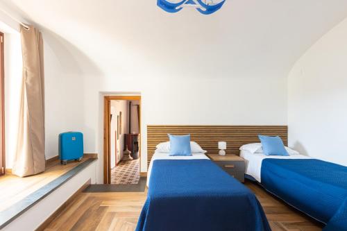 a bedroom with two beds with blue sheets at Il Giardino dei Gigli in Meta