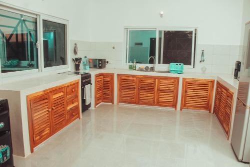 a large kitchen with wooden cabinets and windows at Villa Franet in Watamu