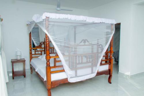 a bedroom with a canopy bed with white curtains at Villa Franet in Watamu