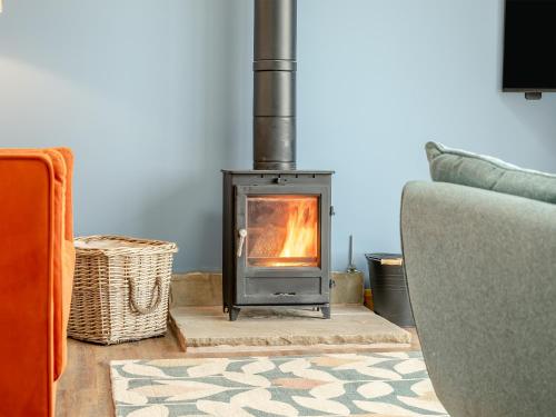 a wood stove in a living room with a couch at Kinder in Mellor