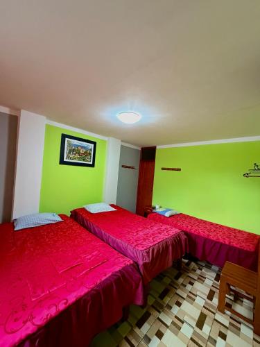 two beds in a room with green and red at HOSTAL GRAU in Churín