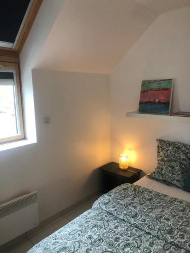 a bedroom with a bed and a lamp on a table at Armorique résidence in Malestroit