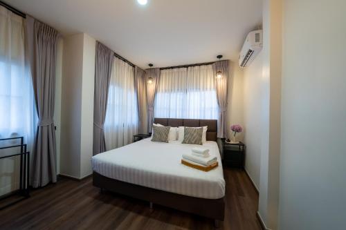 a bedroom with a bed with white sheets and windows at House 148 Patong Pool Villa 4BR Near Beach in Patong Beach