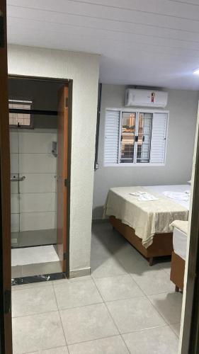 a bedroom with a bed and a window and a shower at HotelItaveraMS in Campo Grande