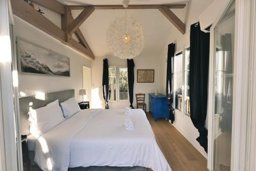 a bedroom with a white bed and a chandelier at Maison Capucine in Hossegor