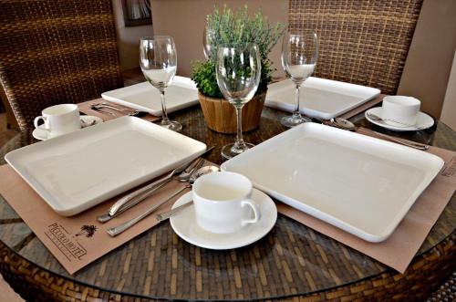 a table with white plates and cups and wine glasses at The Piccolo Hotel of Boracay in Boracay