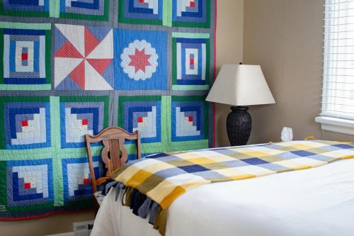 a bedroom with a bed and a wall with a quilt at Our Little Yellow House in Saint Anthony
