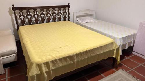 two beds with yellow covers in a room at Pousada Realeza de Itanhaém in Itanhaém