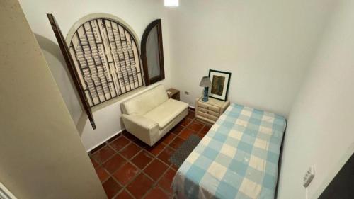 a living room with a white chair and a window at Pousada Realeza de Itanhaém in Itanhaém