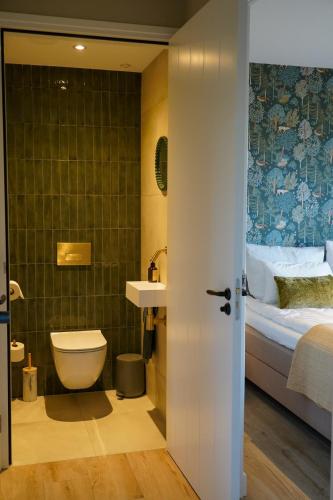 a bathroom with a sink and a toilet and a bed at Landgoed Erve Triesthaar in De Lutte