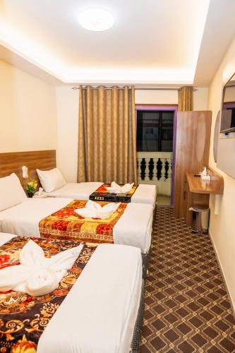 a hotel room with three beds and a window at Al Khaima Hotel in Dubai